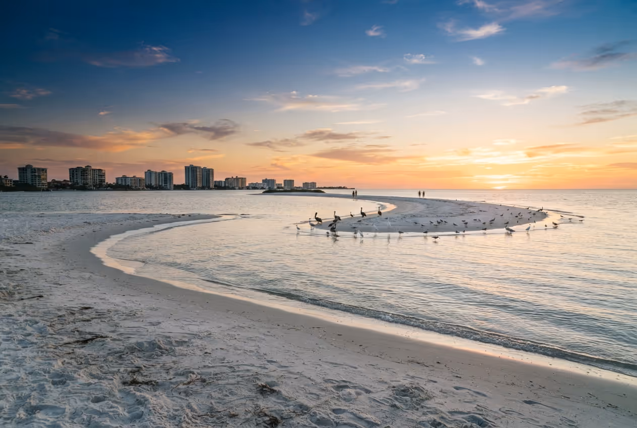 Praia em crescente de Marco Island com o Golfo calmo e a fileira de condomínios altos ao fundo