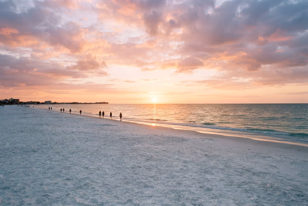 Faixa larga de areia branca de Siesta Key com guarda-sóis coloridos e o Golfo do México calmo ao fundo