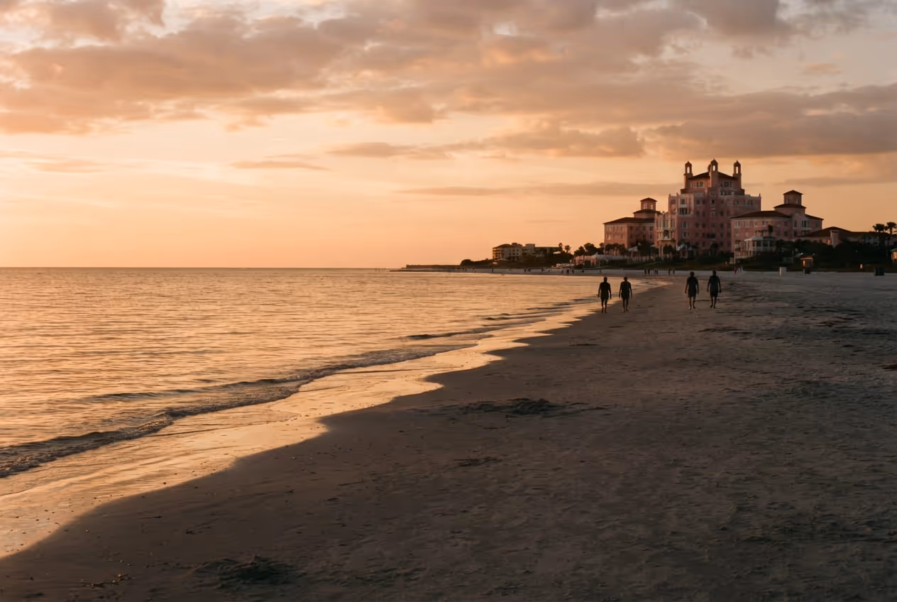 Areia larga de St. Pete Beach ao fim da tarde com o vulto rosa do hotel histórico ao fundo
