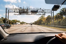 Pórtico de pedágio eletrônico sobre uma rodovia expressa da Flórida, sem cabine e sem cancela, com carros passando em velocidade